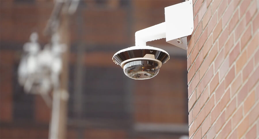 A security camera on the corner of a facility monitoring traffic and motion events.